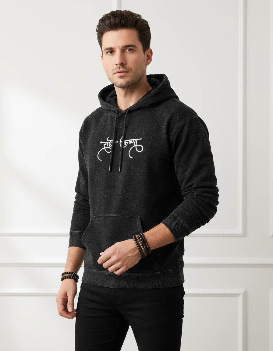 Man wearing a black hoodie with a logo against a white wall