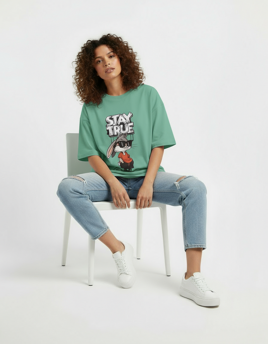 Person wearing a pink t-shirt with a graphic design, sitting on a white chair against a white background