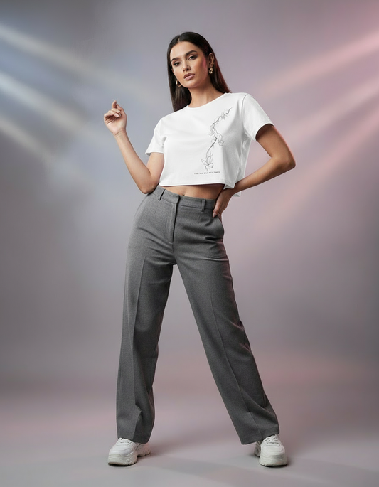 Woman wearing a pink crop top and gray pants against a gradient background